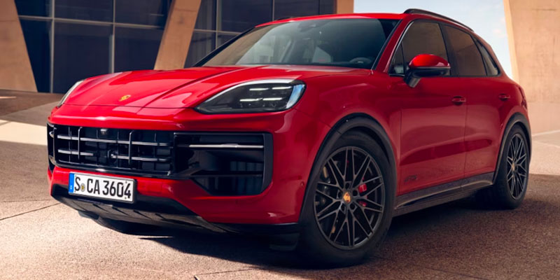Red Porsche Cayenne SUV parked in a modern architectural setting, showcasing sleek design and bold styling.