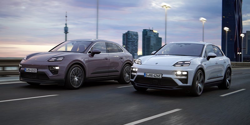 A dreams provence 2025 Porsche All- Electric Macan 4 and a shades ice gray 2025 Porsche All-Electric Macan 4 driving next to one another on the highway at dusk